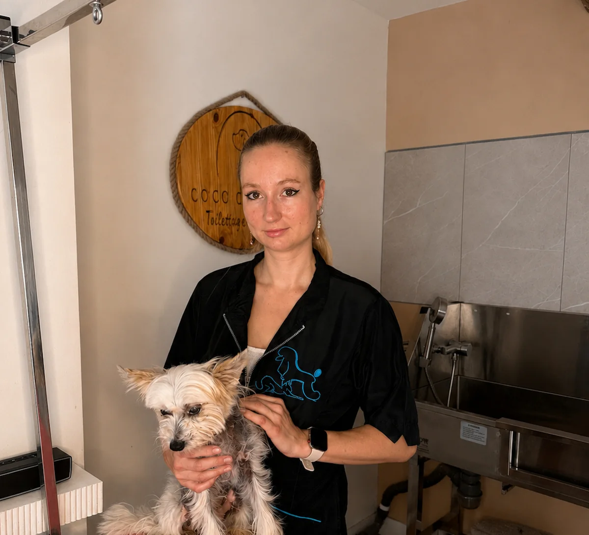 Noémie Castel, les mains posées sur un chien à la table de toilettage